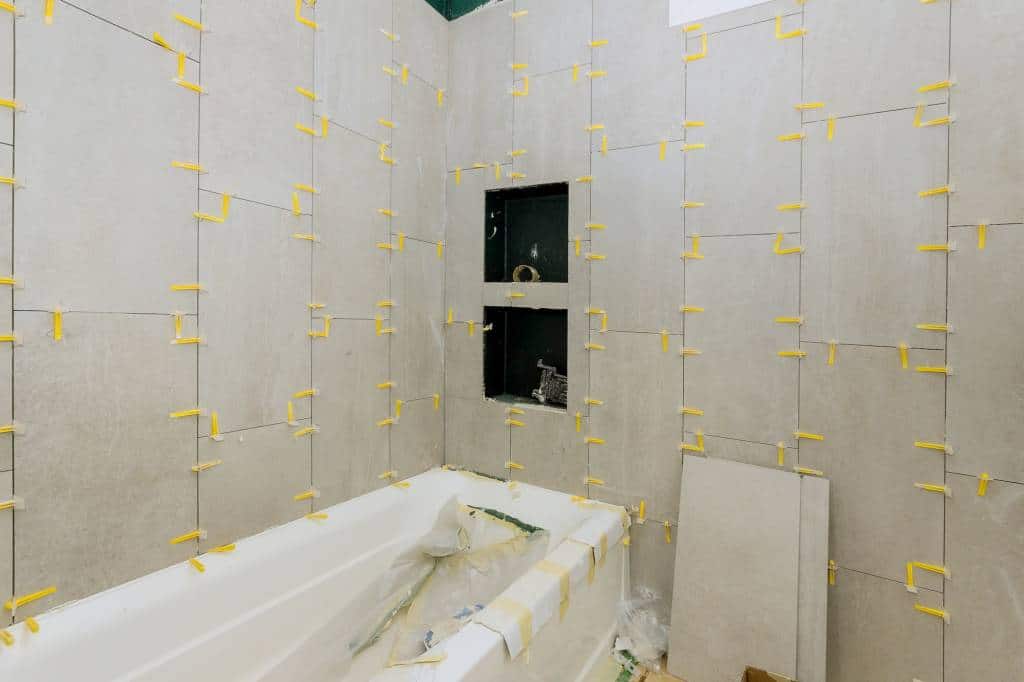 Laying tiles in the bathroom construction floor and wall ceramic tiles installation unfinished