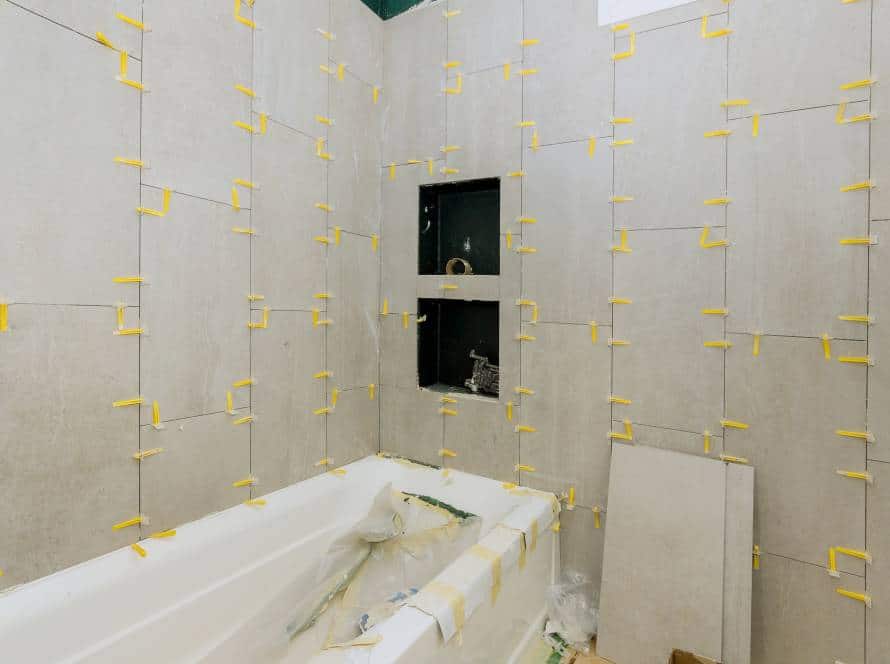 Laying tiles in the bathroom construction floor and wall ceramic tiles installation unfinished