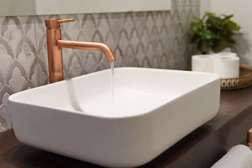 Modern bathroom sink minimalist design, white sink and slow running clean water from the faucet